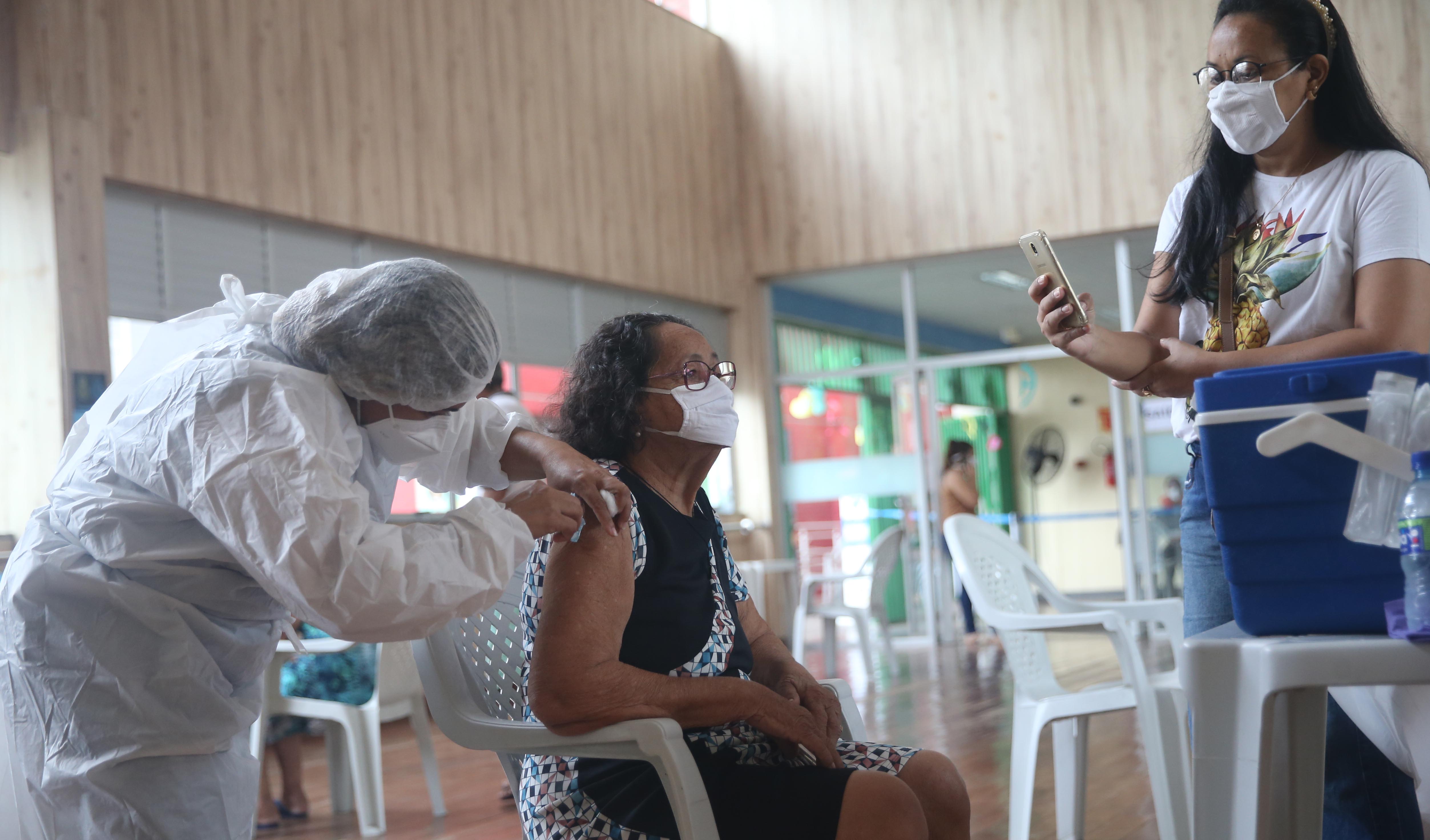 senhora de máscara sendo vacinada